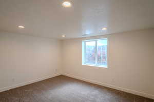Empty room featuring visible vents, dark carpet, baseboards, and recessed lighting