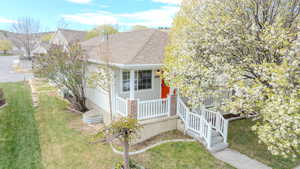 View of front of property featuring a porch, a shingled roof, and a front lawn