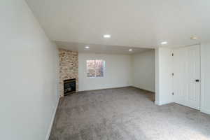 Unfurnished living room featuring a fireplace, baseboards, carpet floors, and a textured ceiling