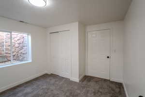 Unfurnished bedroom featuring a textured ceiling, baseboards, visible vents, a closet, and carpet floors