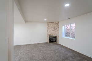 Unfurnished living room featuring recessed lighting, visible vents, carpet floors, baseboards, and a large fireplace