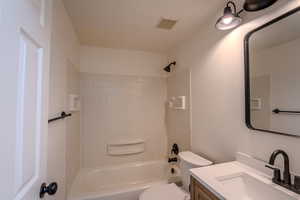 Bathroom featuring shower / washtub combination, visible vents, vanity, and toilet