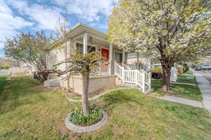 View of front facade featuring covered porch and a front yard