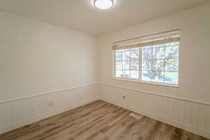 Spare room with light wood finished floors, wainscoting, and visible vents