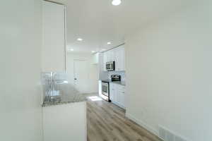 Kitchen featuring a sink, tasteful backsplash, recessed lighting, white cabinetry, and appliances with stainless steel finishes
