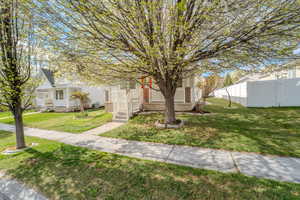 View of front of home featuring fence, covered porch, and a front yard