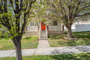 Obstructed view of property with covered porch, a front yard, and brick siding