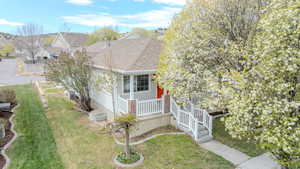 View of property exterior featuring a lawn, a shingled roof, and covered porch