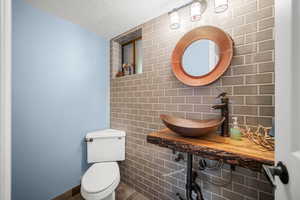 Bathroom with a textured ceiling, toilet, and a sink