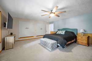 Bedroom featuring light colored carpet, a ceiling fan, and a textured ceiling