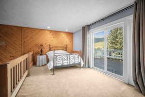 Bedroom featuring carpet flooring, a textured ceiling, access to exterior, recessed lighting, and wooden walls