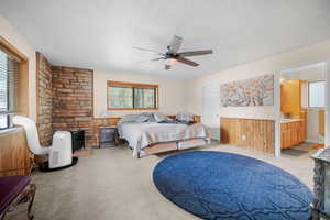 Bedroom featuring light colored carpet, a ceiling fan, wainscoting, and a textured ceiling