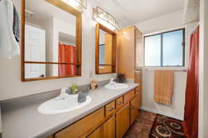 Bathroom with baseboards, stone finish floor, a sink, and double vanity