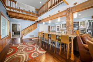 Kitchen featuring hardwood / wood-style floors, light stone counters, stainless steel fridge with ice dispenser, visible vents, and glass insert cabinets