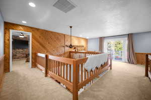 Hall featuring an upstairs landing, light colored carpet, wood walls, visible vents, and recessed lighting