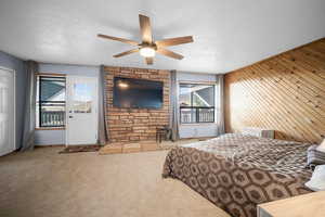 Carpeted bedroom featuring access to outside, a textured ceiling, ceiling fan, and multiple windows