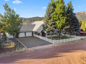 View of front of property featuring a chimney, aphalt driveway, fence, a mountain view, and a garage