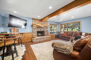 Living room with a wainscoted wall, recessed lighting, beamed ceiling, hardwood / wood-style floors, and a fireplace