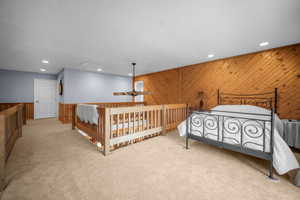 Bedroom featuring carpet floors, wooden walls, and recessed lighting