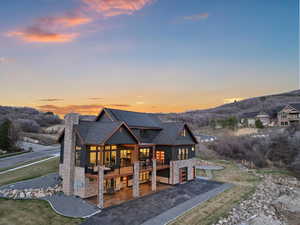 Back of property featuring a chimney, driveway, stone siding, an attached garage, and a mountain view