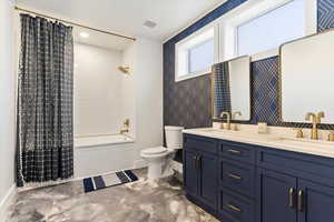 Bathroom featuring baseboards, a sink, double vanity, and toilet