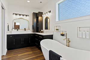 Bathroom featuring a soaking tub, wood finished floors, recessed lighting, and vanity