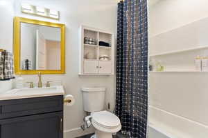 Bathroom with baseboards, shower / tub combo, toilet, and vanity