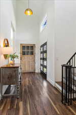 Foyer entrance featuring baseboards, a towering ceiling, dark wood-style floors, and stairway