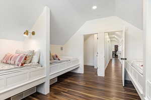 Bedroom featuring vaulted ceiling, visible vents, and dark wood-type flooring