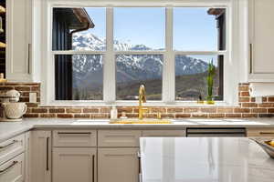 Interior details with backsplash, a mountain view, white cabinetry, and a sink