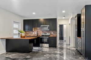 Kitchen with stainless steel appliances, backsplash, visible vents, a sink, and butcher block counters