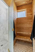 Bathroom featuring wood walls and a stall shower