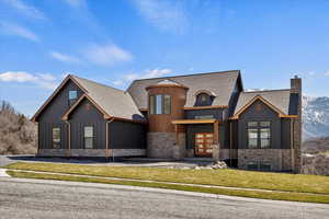 View of front of house with a chimney, stone siding, board and batten siding, french doors, and a front yard