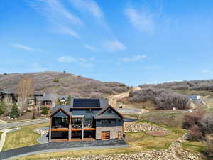 Exterior space featuring a yard, solar panels, a deck with mountain view, and stone siding