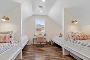 Bedroom with lofted ceiling, visible vents, baseboards, and dark wood-style flooring