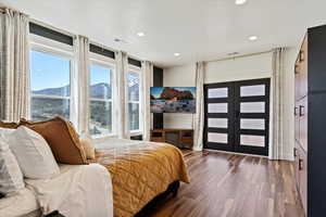 Bedroom with recessed lighting, wood finished floors, visible vents, and french doors
