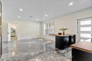 Interior space with recessed lighting, wooden counters, and dark cabinets
