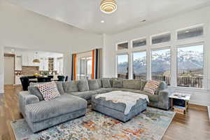 Living area with a towering ceiling, wood finished floors, visible vents, a mountain view, and baseboards