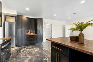 Bar with marble finish floor, recessed lighting, visible vents, and freestanding refrigerator