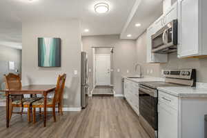 Kitchen featuring light wood finished floors, baseboards, stainless steel appliances, and a sink
