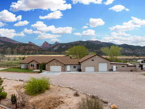 View of front of house with an attached garage, gravel driveway, fence, and a mountain view