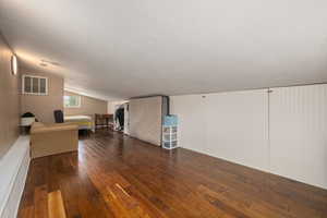 Additional living space with lofted ceiling, visible vents, a textured ceiling, and wood-type flooring