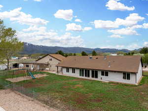 Back of house featuring a mountain view, fence, a patio area, and a playground