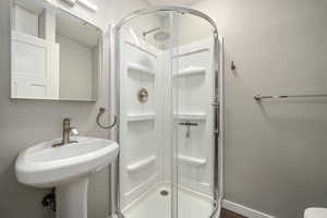 Full bathroom featuring baseboards, a stall shower, and a sink