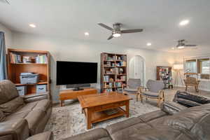Living area featuring arched walkways, a ceiling fan, baseboards, and recessed lighting