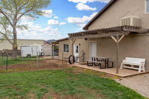 Back of property featuring a pergola, central air condition unit, a lawn, a deck, and fence