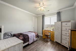 Bedroom featuring dark wood-style floors, a ceiling fan, baseboards, ornamental molding, and visible vents