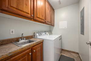 Washroom with washer and clothes dryer, visible vents, a sink, baseboards, and cabinet space