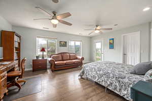 Bedroom featuring a ceiling fan, wood finished floors, baseboards, access to exterior, and visible vents