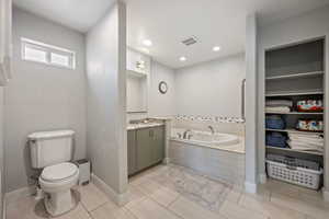 Bathroom featuring a bath, vanity, baseboards, toilet, and visible vents